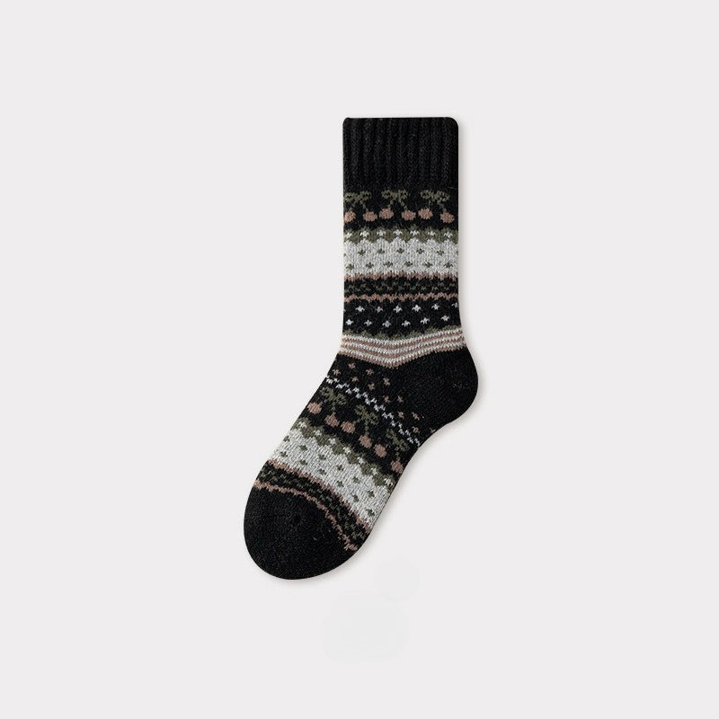 Black Nordic woolen sock with traditional pattern in muted pink, green, and white.