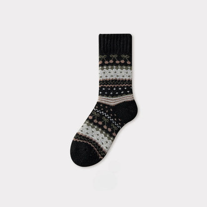 Black Nordic woolen sock with traditional pattern in muted pink, green, and white.