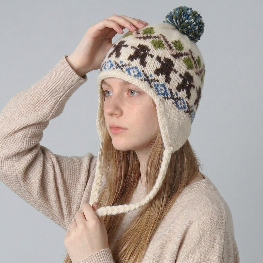 Woman wearing the cream gingerbread man Nordic knit ear-flap hat with a pom-pom