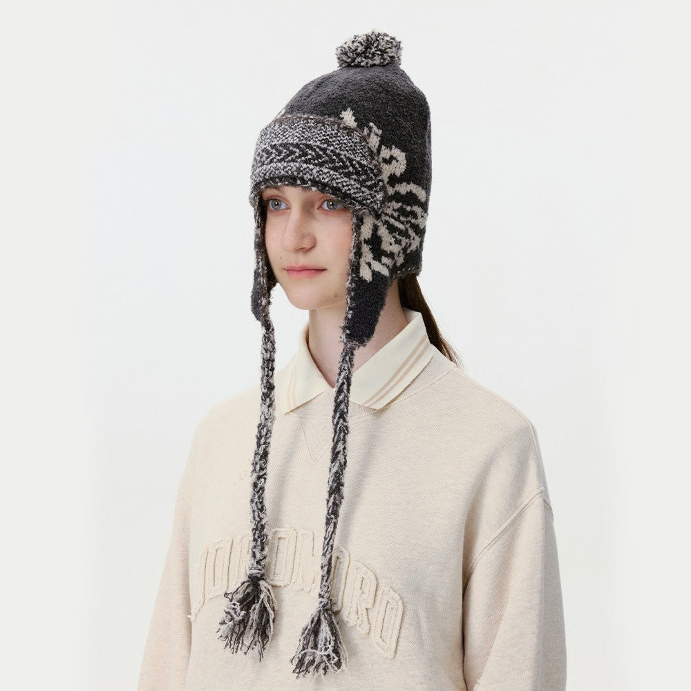 Model wearing the black knitted trapper hat with pom-pom and braided tassel ties