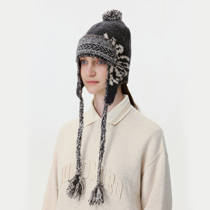 Model wearing the black knitted trapper hat with pom-pom and braided tassel ties