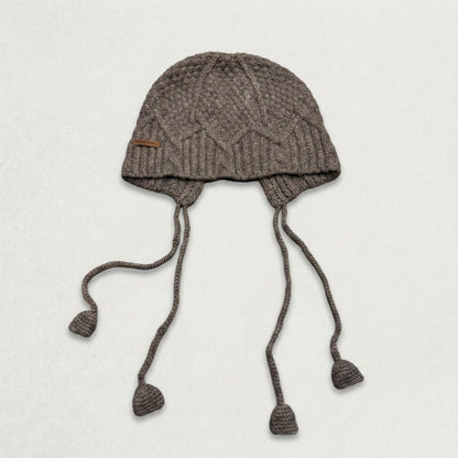 Grey cable-knit jellyfish hat with four dangling cords, laid flat