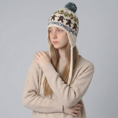 Woman in a cream jumper wearing the cream gingerbread man ear-flap hat