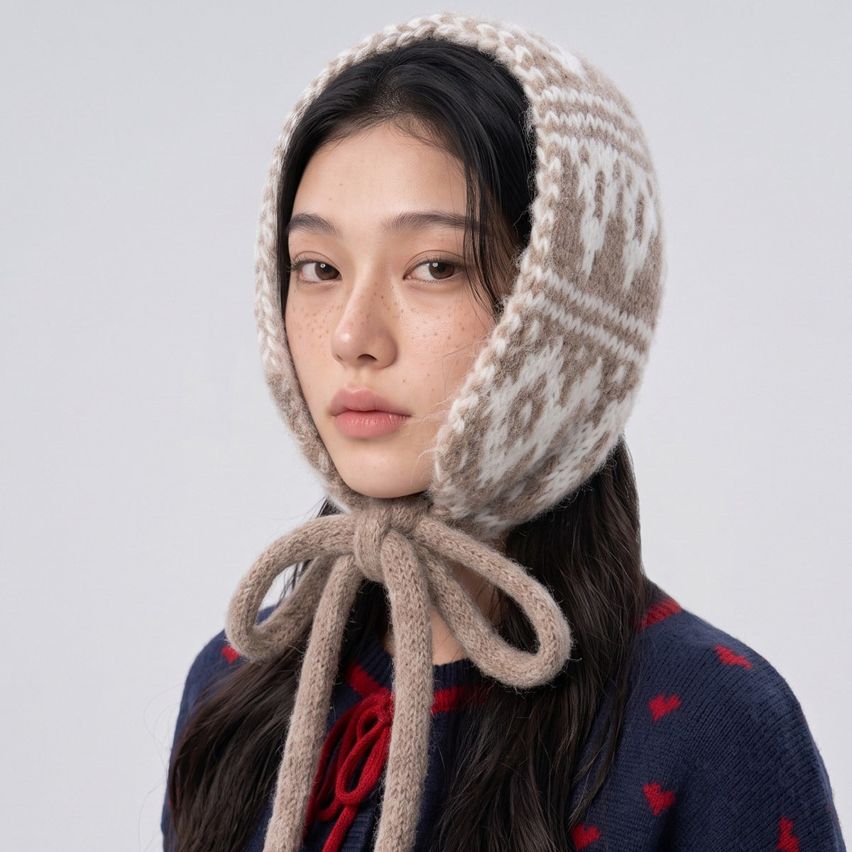 Woman wearing the camel and cream Fair Isle knitted hood tied in a bow