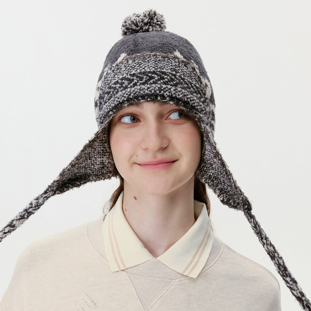 Smiling model in the black trapper hat with the ear flap ties spread out