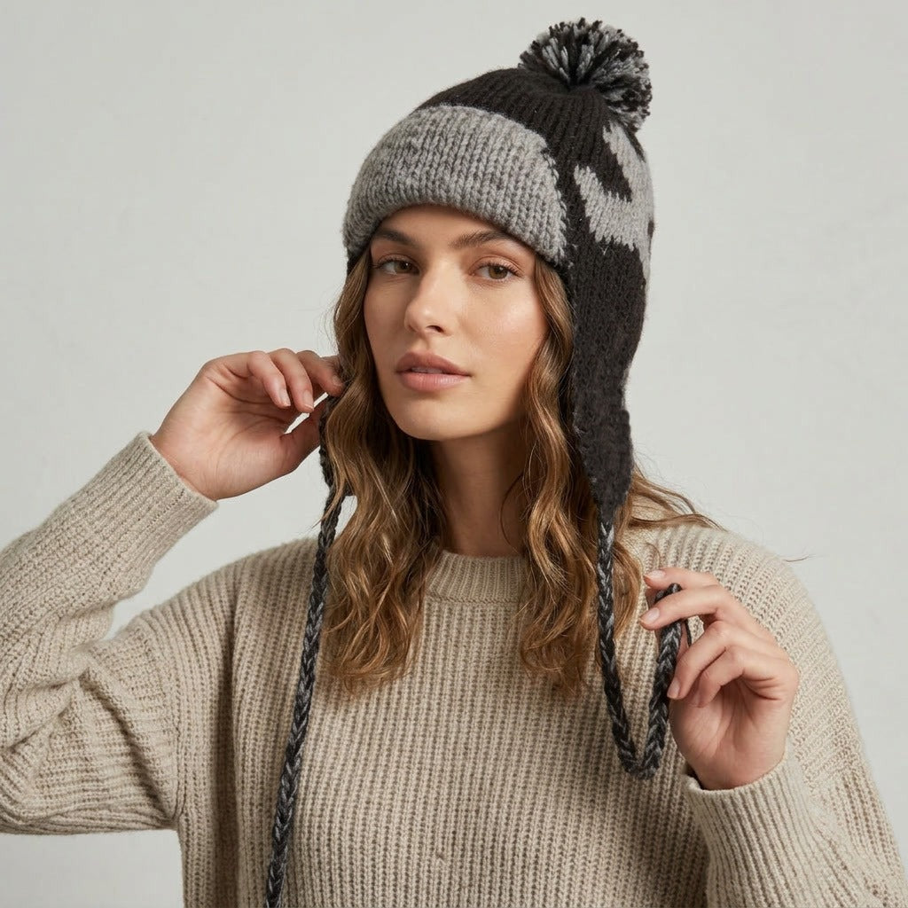 Woman adjusting the ear flap of the black heart pattern hat