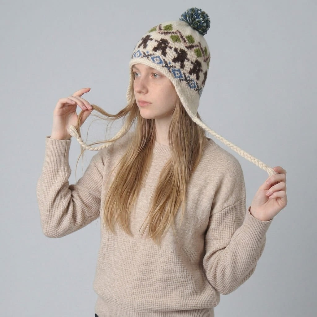 Woman holding the braided ties of the cream gingerbread man ear-flap hat