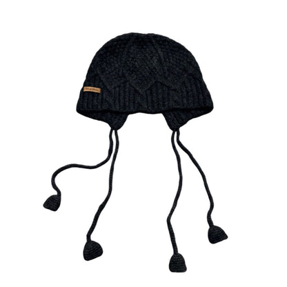 Black cable-knit jellyfish hat with dangling cords on a white background
