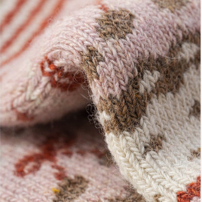 Close-up of soft pink Nordic woolen socks with brown, white, and orange traditional patterns.