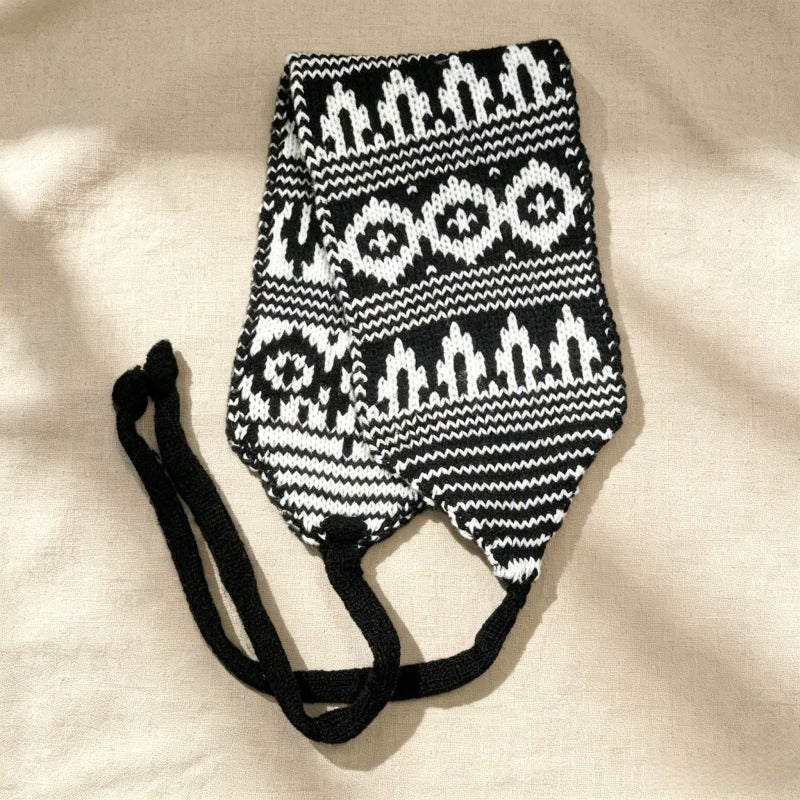Black and white Fair Isle knitted hood laid flat with its long ties