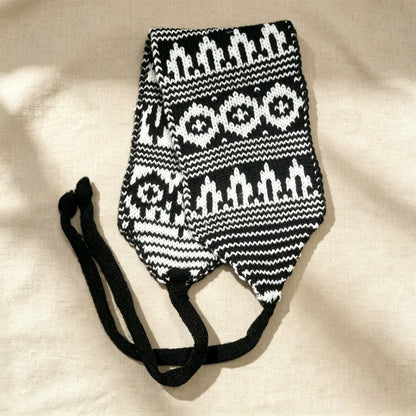 Black and white Fair Isle knitted hood laid flat with its long ties