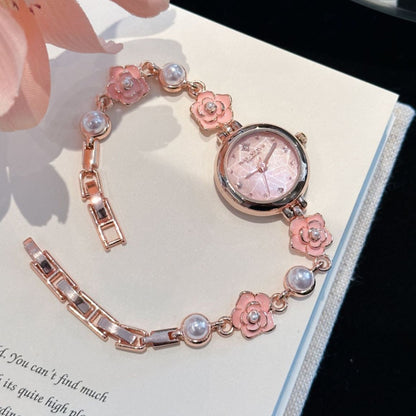 Rose gold camellia pearl bracelet watch with pink flowers on an open book