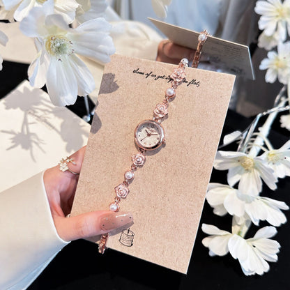 Rose gold camellia pearl bracelet watch on a card beside white flowers
