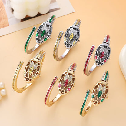 Six crystal snake bangle watches in gold and silver with green, red and yellow stones