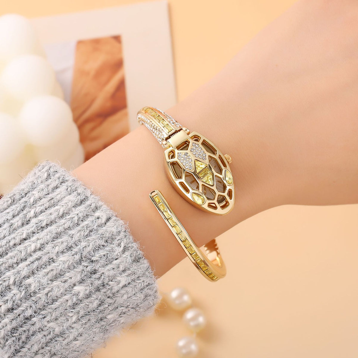 Gold snake bangle watch with yellow crystals worn on the wrist