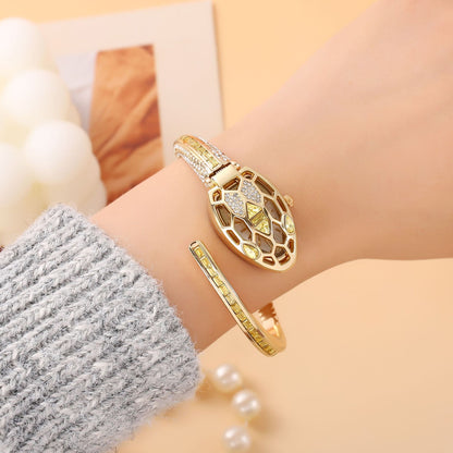 Gold snake bangle watch with yellow crystals worn on the wrist