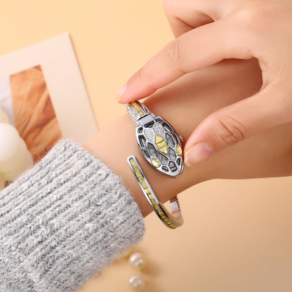 Hand adjusting a silver snake bangle watch with yellow crystals on the wrist