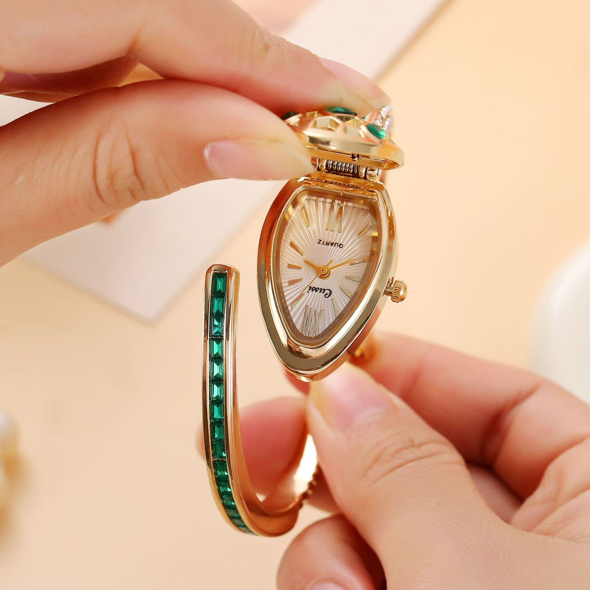 Snake head lid lifted to show a teardrop dial with Roman numerals