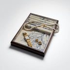 Jewelry set including a gold watch, pearl necklace, and earrings in an open jewelry box on a white background.