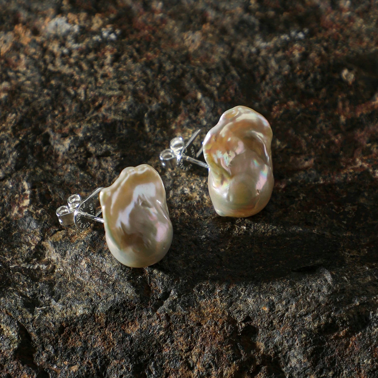 Pearl earrings on a dark stone surface 