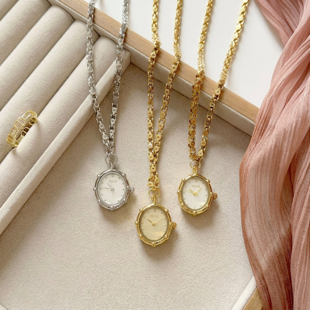 Silver and gold oval necklace watches displayed side by side