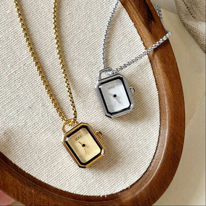 Gold and silver rectangle necklace watches on a wooden tray