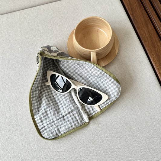 Open embroidered glasses case with a gingham lining and sunglasses inside