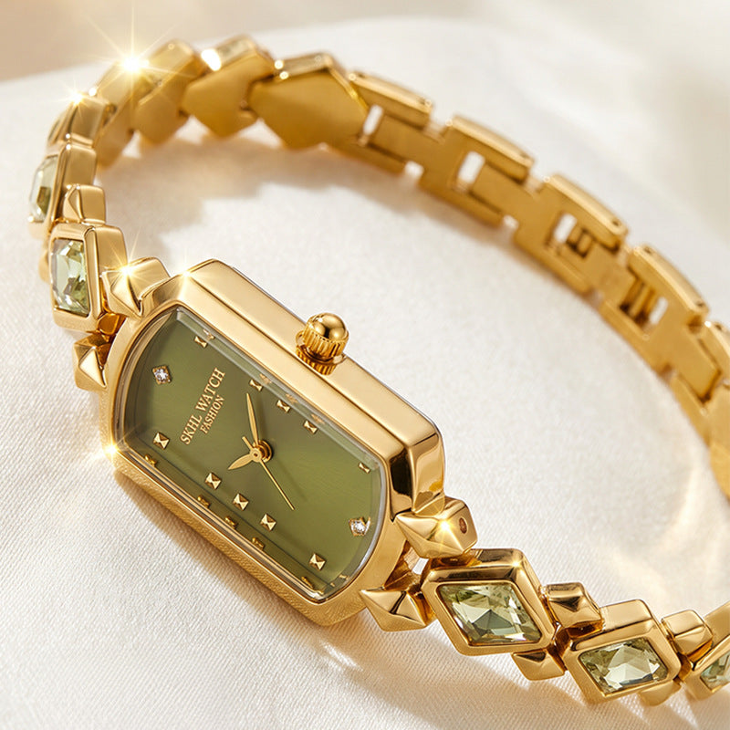 vintage women's gold-plated quartz jewelry watch featuring a barrel-shaped olive green dial and an interlocking rhombus link bracelet inlaid with faceted green crystals