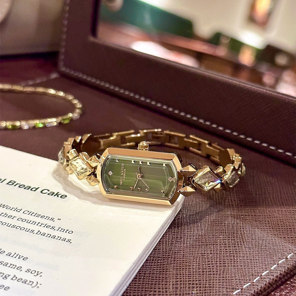 vintage women's gold-plated quartz jewelry watch featuring a barrel-shaped olive green dial and an interlocking rhombus link bracelet inlaid with faceted green crystals