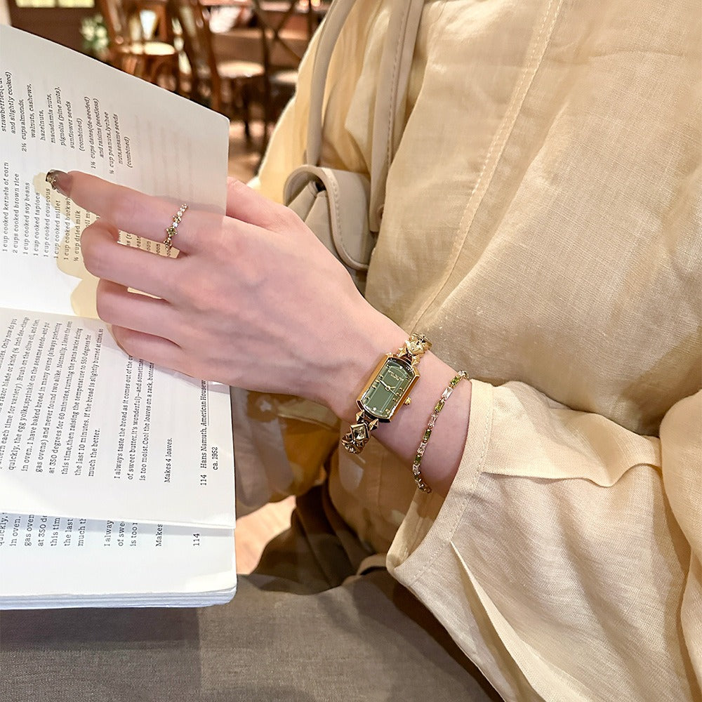 vintage women's gold-plated quartz jewelry watch featuring a barrel-shaped olive green dial and an interlocking rhombus link bracelet inlaid with faceted green crystals