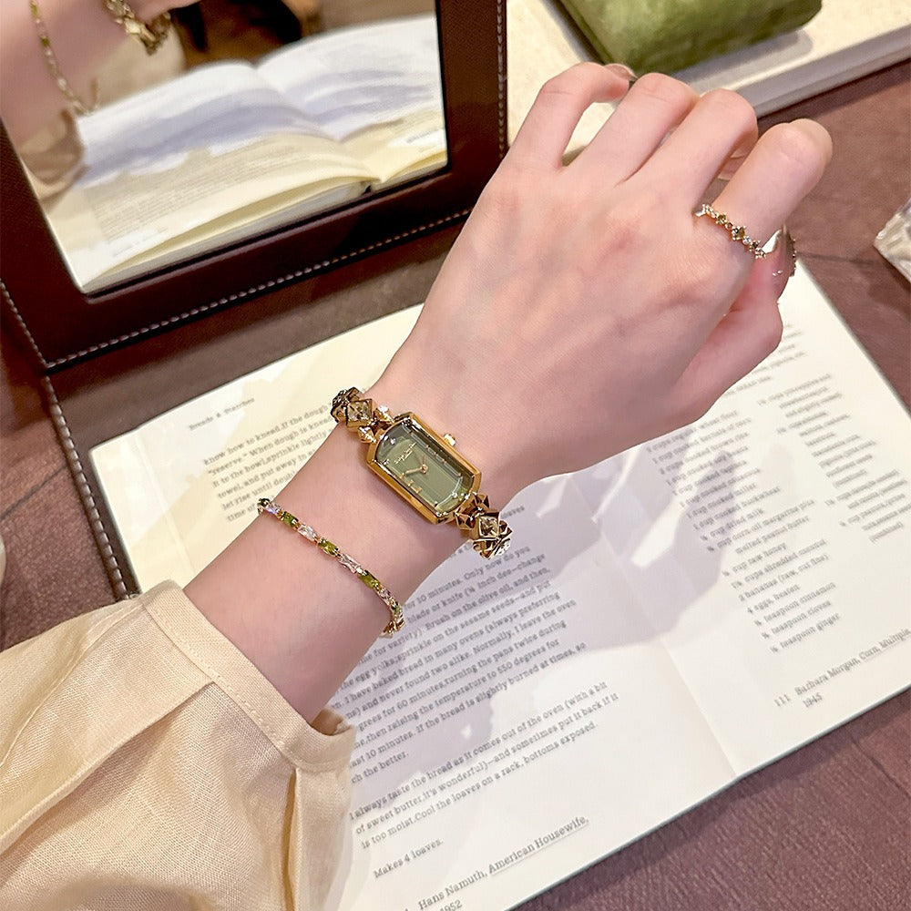 vintage women's gold-plated quartz jewelry watch featuring a barrel-shaped olive green dial and an interlocking rhombus link bracelet inlaid with faceted green crystals