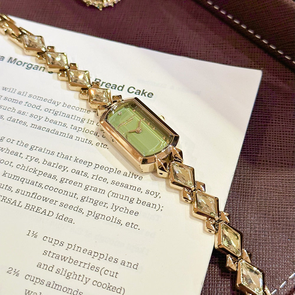 vintage women's gold-plated quartz jewelry watch featuring a barrel-shaped olive green dial and an interlocking rhombus link bracelet inlaid with faceted green crystals