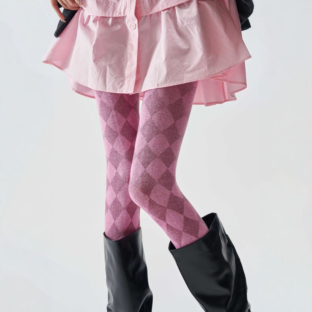 Women's tartan thermal tights in pink with a diamond check pattern, worn with black knee-high boots